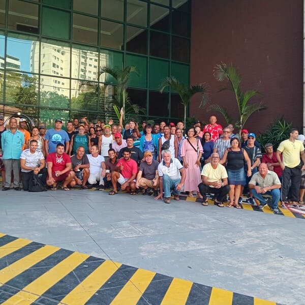 Palestra em um auditório, com uma mulher falando para pescadores e representantes da comunidade.
