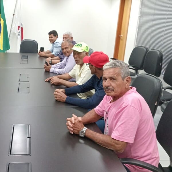 Dois palestrantes discutindo em um evento, um deles segurando um microfone enquanto fala para a plateia.