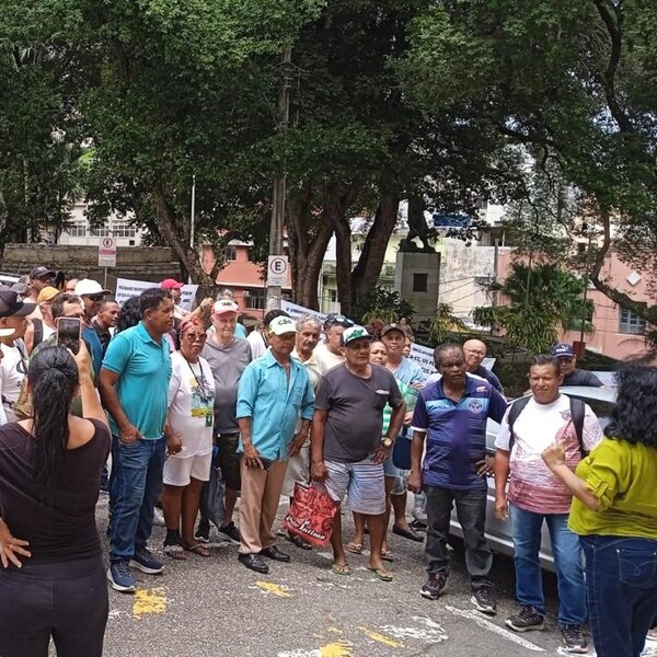 Vista semelhante à imagem 7, com mais foco em um grupo de homens posando para a foto em uma rua com árvores.